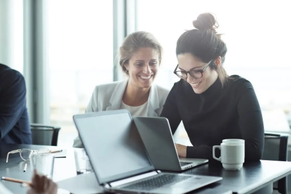 Smiling colleagues looking at a laptop 